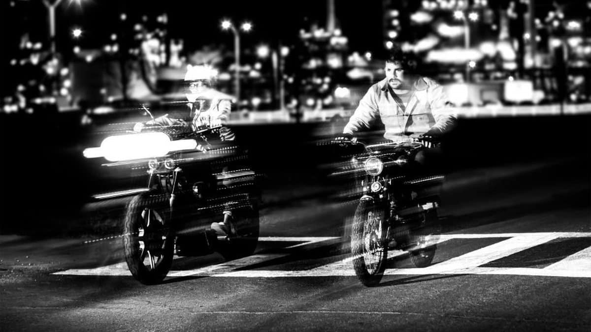 Motorcycle at a road crossing at night, photographed in black and white